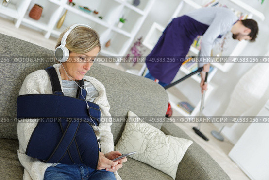 disabled woman using a cellphone while assistant cleaning. Стоковое фото, агентство Ingram Publishing / Фотобанк Лори