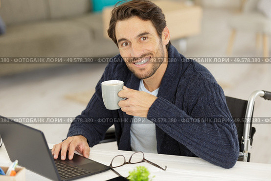 disabled young man using laptop and drinking coffee. Стоковое фото, агентство Ingram Publishing / Фотобанк Лори
