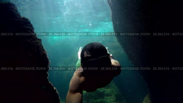 Diver dives into the water swims between the rocks and floats up and beats in the boat. Стоковое видео, видеограф Tatiana Kravchenko / Фотобанк Лори