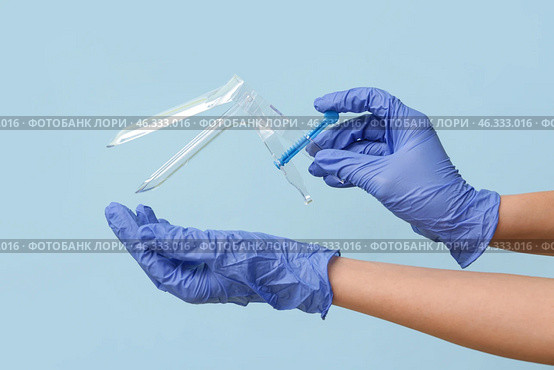 Doctor hands in medical gloves with gynecological speculum on blue background. Стоковое фото, фотограф Pixel_shot / Фотобанк Лори