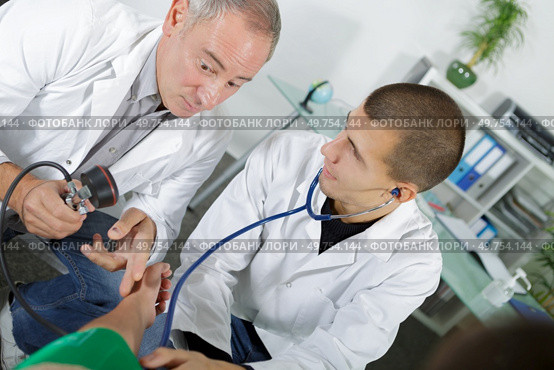 doctor in scrubs taking the blood pressure of a patient. Стоковое фото, агентство Ingram Publishing / Фотобанк Лори