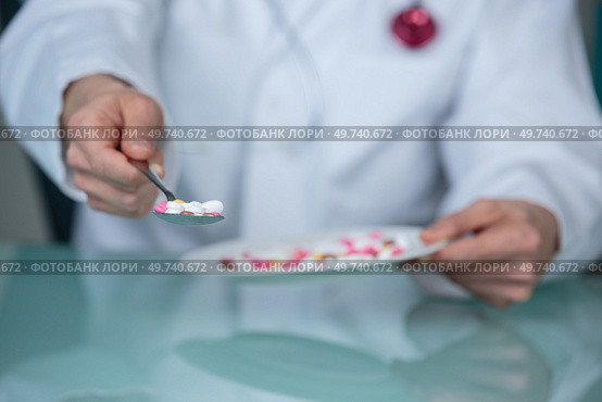 doctor offering spoonful of tablets. Стоковое фото, агентство Ingram Publishing / Фотобанк Лори
