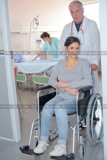 Doctor wheeling patient in wheelchair. Стоковое фото, агентство Ingram Publishing / Фотобанк Лори