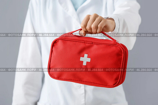 Doctor with first aid kit on grey background. Стоковое фото, фотограф Pixel_shot / Фотобанк Лори