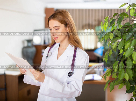 Doctor woman standing in hall with sheets of paper in hands. Стоковое фото, фотограф Яков Филимонов / Фотобанк Лори