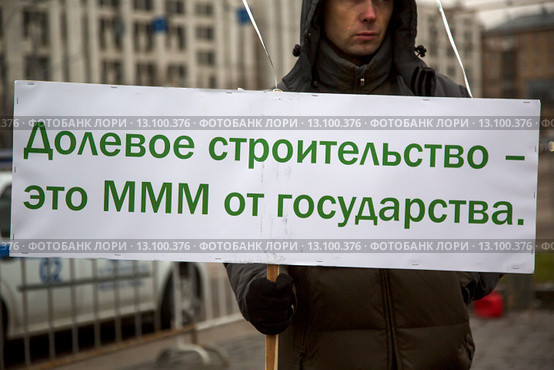 Дольщик строительной компании держит плакат на митинге обманутых дольщиков Московского региона в городе Москве на площади Краснопресненской заставы, Россия (2015 год). Редакционное фото, фотограф Николай Винокуров / Фотобанк Лори