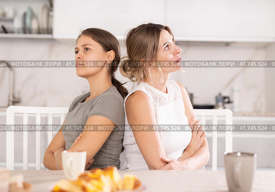 Domestic quarrel - two sisters quarreled in kitchen, sitting back to back. Стоковое фото, фотограф Яков Филимонов / Фотобанк Лори
