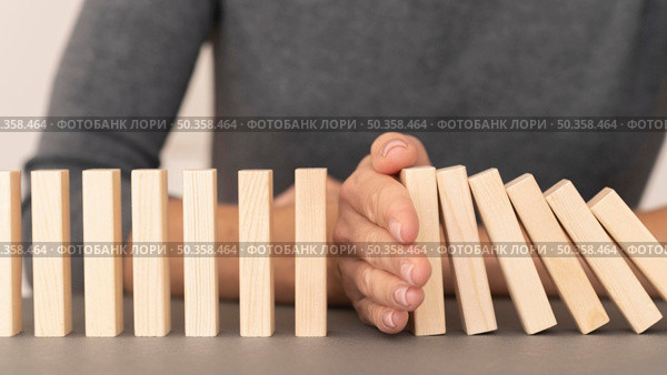 domino made with wooden pieces representing finances struggles. Стоковое фото, агентство Ingram Publishing / Фотобанк Лори
