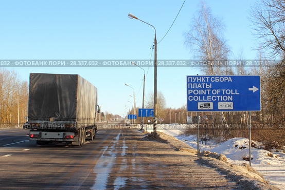Дорожный указатель Пункт сбора платы Платон на фоне грузового автомобиля с прицепом зимой (2017 год). Редакционное фото, фотограф Илья Илмарин / Фотобанк Лори