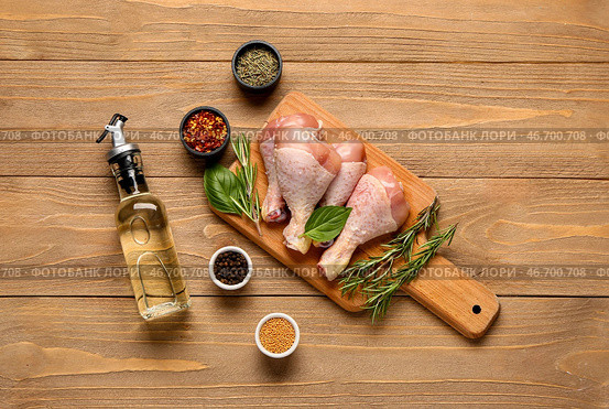 Доска для резки сырых куриных ножек, травами, специями и маслом на деревянном фоне. Стоковое фото, фотограф Pixel_shot / Фотобанк Лори