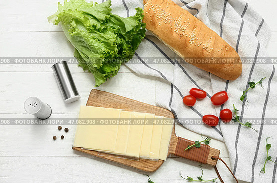 Доска с ломтиками вкусного плавленого сыра, свежими овощами и хлебом на белом деревянном столе. Стоковое фото, фотограф Pixel_shot / Фотобанк Лори
