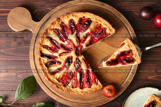 Доска с вкусным сливовым пирогом на деревянном фоне. Стоковое фото, фотограф Pixel_shot / Фотобанк Лори
