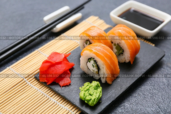 Доска с вкусными суши-роллами, маринованным имбирем и васаби на черном фоне, крупным планом. Стоковое фото, фотограф Pixel_shot / Фотобанк Лори