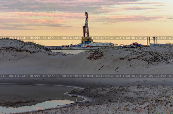 Drilling oil and gas wells in desert terrain. Sand hills, sparse vegetation. Beautiful sky. Infrastructure of the drilling rig. Стоковое фото, фотограф Владимир Ендовицкий / Фотобанк Лори