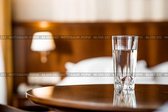 Drinks. A glass of crystal clear fresh drinking water on the table in the interior of the hotel room. Стоковое фото, фотограф Photojuli / Фотобанк Лори