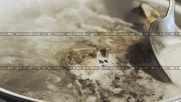 During the boiling of the broth, remove the film from the surface with a spoon. Стоковое видео, видеограф Ярославский Максим / Фотобанк Лори