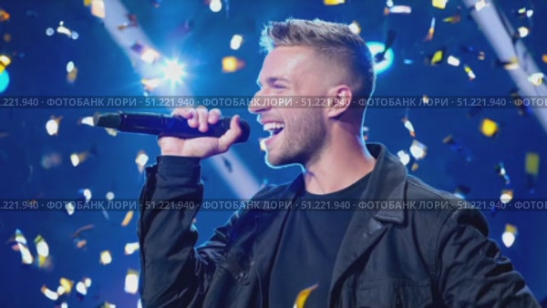 Dynamic vocalist performing onstage, wearing black attire, gripping microphone while golden confetti cascading during high energy musical concert. Стоковое AI-видео, аниматор Юрий Поздников / Фотобанк Лори