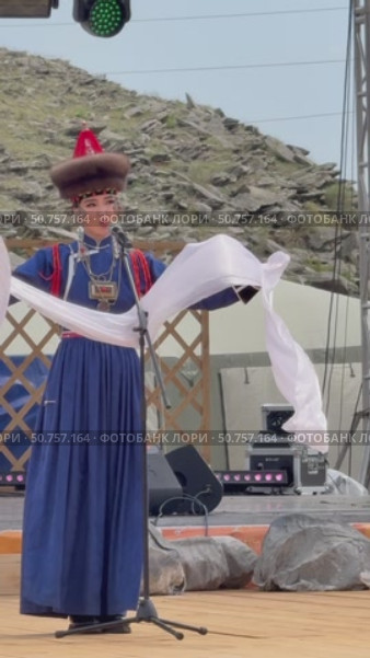 ELANTSY, IRKUTSK REGION, RUSSIA - July 5, 2025: Erdy Games – festival of nomadic peoples of Eurasia on coast of Baikal Lake. Vertical video of Buryat girl in national blue costume with hadak on open stage in Beauty Contest. Редакционное видео, видеограф Виктория Катьянова / Фотобанк Лори