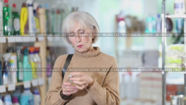 Elderly housewife chooses perfume or aromatic incense in a supermarket. Стоковое видео, видеограф Яков Филимонов / Фотобанк Лори