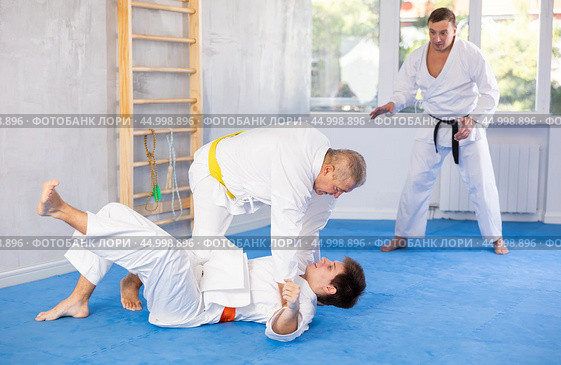 Elderly karate instructor demonstrating martial arts techniques in sparring with young fighter. Стоковое фото, фотограф Яков Филимонов / Фотобанк Лори