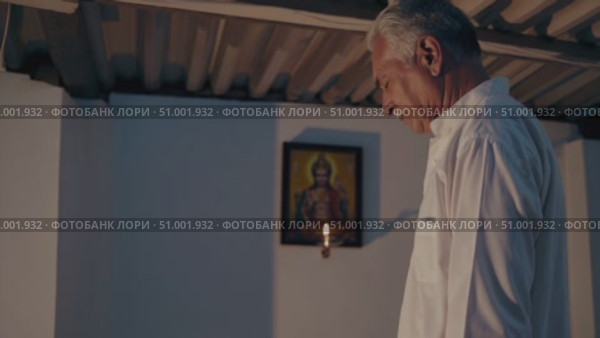 Elderly male praying silently in shadowy room, focused on religious painting softly illuminated by candlelight, expressing deep spiritual contemplation. Стоковое AI-видео, аниматор Данил Руденко / Фотобанк Лори