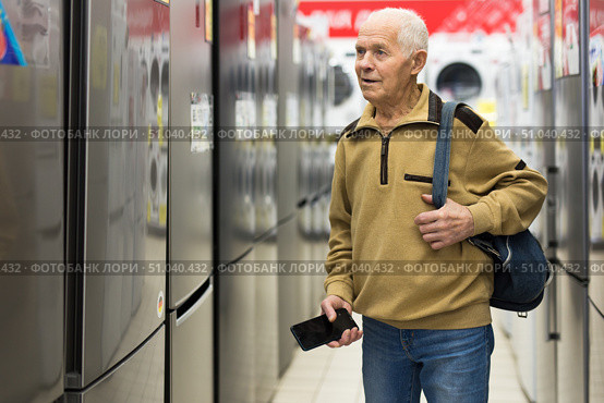 elderly man choosing refrigerator in showroom of electrical appliance store. Стоковое фото, фотограф Татьяна Яцевич / Фотобанк Лори