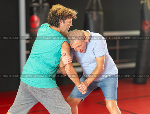 Elderly man learning self-defense grips and escapes at gym. Стоковое фото, фотограф Яков Филимонов / Фотобанк Лори