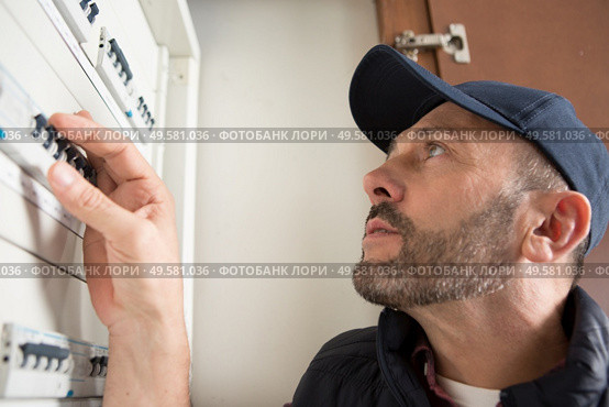 electrician checking fuses in circuit breaker box. Стоковое фото, агентство Ingram Publishing / Фотобанк Лори