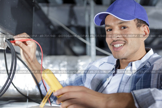 electrician using multimeter in roof space. Стоковое фото, агентство Ingram Publishing / Фотобанк Лори