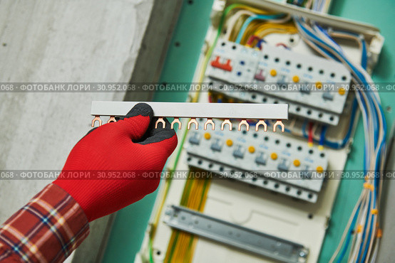 Electrician works with power rail in switchbox. current breaker installation. Стоковое фото, фотограф Дмитрий Калиновский / Фотобанк Лори