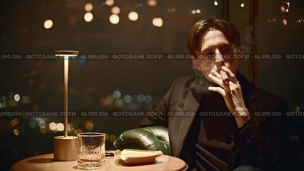 Elegant man in suit smokes cigar in restaurant. Стоковое фото, фотограф David Kashakhi / Фотобанк Лори