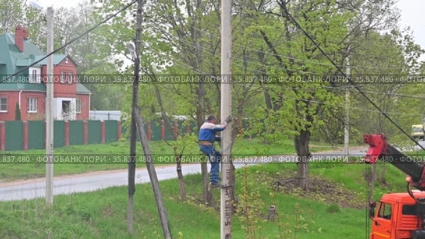 Электромонтажник спускается по бетонному столбу с помощью монтерских когтей (лазы монтерские, кошки) (2021 год). Редакционное видео, видеограф Владимир Литвинов / Фотобанк Лори