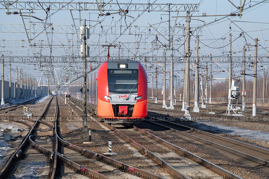 Электропоезд ЭС2Г-144 "Ласточка" в движении солнечным мартовским днем. Вид спереди. Октябрьская железная дорога (2024 год). Редакционное фото, фотограф Виктор Карасев / Фотобанк Лори