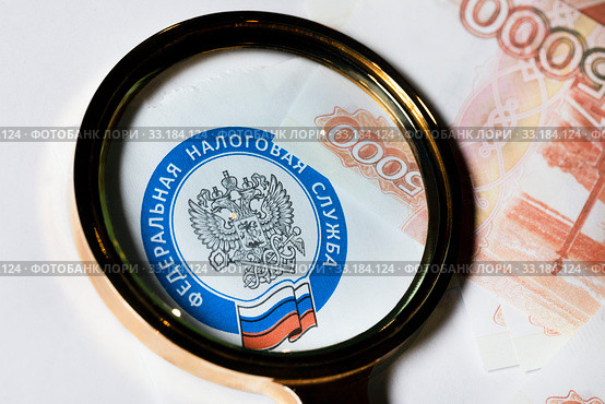 Эмблема Федеральной Налоговой службы Российской Федерации под лупой на фоне 5000 купюр. Стоковое фото, фотограф Николай Винокуров / Фотобанк Лори