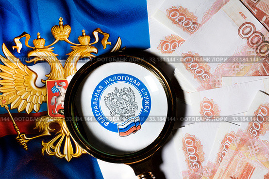 Эмблема Федеральной Налоговой службы Российской Федерации под лупой на фоне герба Российской Федерации и 5000 купюр. Стоковое фото, фотограф Николай Винокуров / Фотобанк Лори