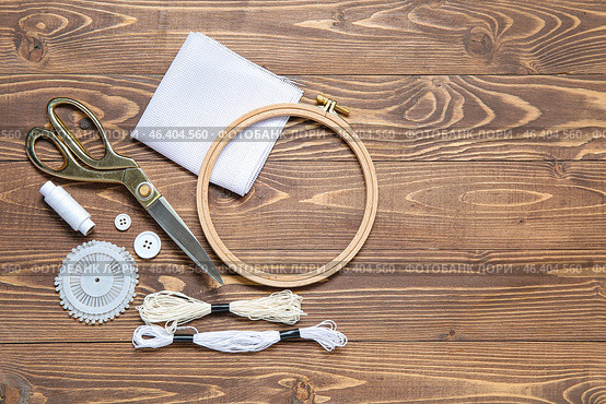Embroidery hoop with canvas, scissors and mouline threads on brown wooden background. Стоковое фото, фотограф Pixel_shot / Фотобанк Лори
