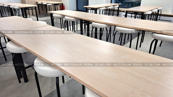 Empty classroom with wooden desks and white chairs in modern educational setting. Стоковое фото, фотограф Zakharova Natasha / Фотобанк Лори