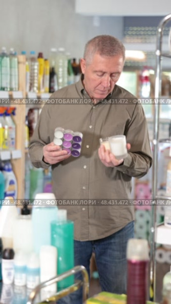 European chooses with interest scented candles made of paraffin and soy wax in the household section of a supermarket. Стоковое видео, видеограф Яков Филимонов / Фотобанк Лори
