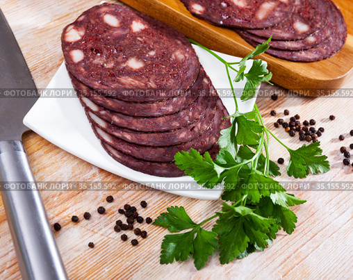 European cuisine blood pudding served with parley on white plate on wooden table. Стоковое фото, фотограф Яков Филимонов / Фотобанк Лори