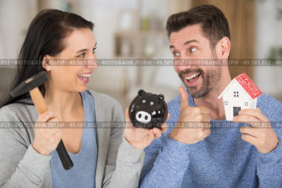excited couple smashing piggybank to invest in a house. Стоковое фото, агентство Ingram Publishing / Фотобанк Лори