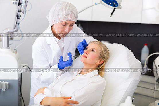 Experienced female cosmetologist performing face contouring injections to woman. Стоковое фото, фотограф Яков Филимонов / Фотобанк Лори