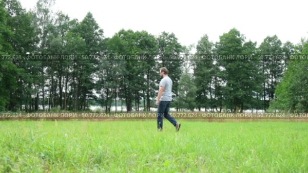 Exploring Nature a Hiker with backpack Strolling Through a Beautiful Field Beneath Vast Blue Sky. Tourist man traverses a scenic field, clear blue sky. Adventure and exploration concept. One person. Стоковое видео, видеограф Марина Демидюк / Фотобанк Лори