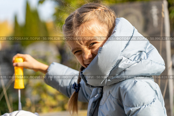 Expressive Portrait of a Young Girl Playing with Bubble Wand, Wearing Padded Jacket in Outdoor Setting. Стоковое фото, фотограф Данила Большаков / Фотобанк Лори