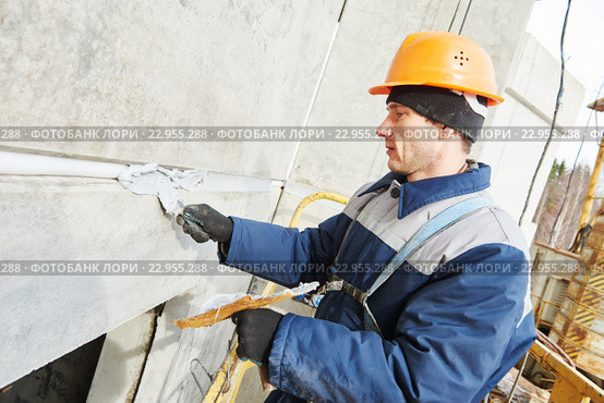Facade plasterer sealing joint of building wall with putty mastic. Стоковое фото, фотограф Дмитрий Калиновский / Фотобанк Лори