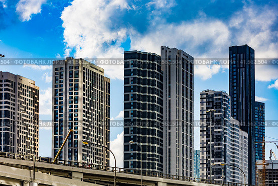 Facades of new residential buildings on Mukomolnyy Proyezd, 2 and blue sky with white clouds. Modern multi-storey residential houses in Moscow (2022 год). Редакционное фото, фотограф Константин Григорьев / Фотобанк Лори