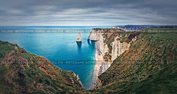 Falaise d’Aval limestone cliffs washed by La Manche channel waters. Beautiful coastline panorama with view to the famous rock Aiguille of Etretat in Normandy, France. Стоковое фото, агентство Ingram Publishing / Фотобанк Лори