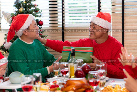 Family members are exchanging gifts with each other in the dinner time during the Christmas holiday at home. Стоковое фото, агентство Ingram Publishing / Фотобанк Лори