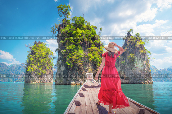 Famous tourist destinations view Thai - Woman solo traveler in red dress on Traditional Thai Longtail boat admiring a famous travel spot Thailand Three Rocks on Cheo Lan Lake in Khaosok Park in Surat Thani Province. Стоковое фото, фотограф Владимир Разгуляев / Фотобанк Лори
