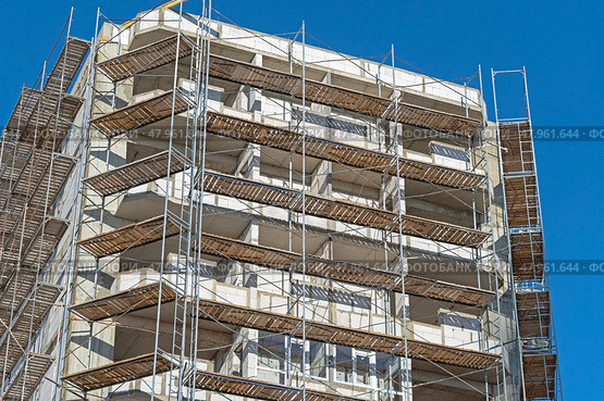 Фасад здания с установленными строительными лесами. Building under construction in scaffolding around the house for cement plastering work on the high outer wall. Стоковое фото, фотограф Татьяна Д / Фотобанк Лори