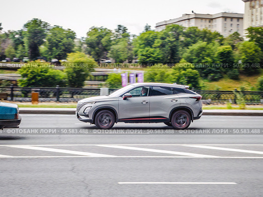 Fast moving car Omoda C5 on the city road. Chinese SUV outdoors in motion, side view. Редакционное фото, фотограф Константин Григорьев / Фотобанк Лори